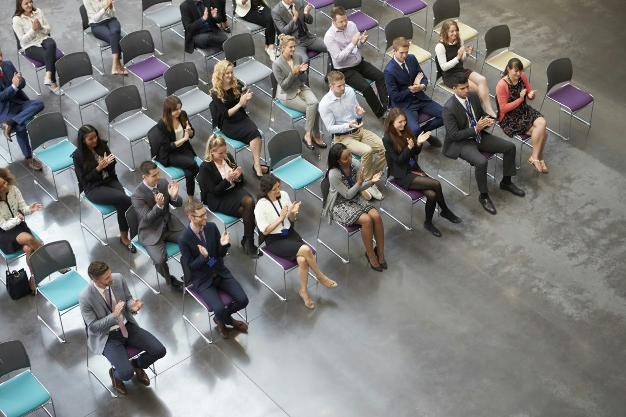 overhead-view-of-audience-applauding-speaker-at-conference.jpg